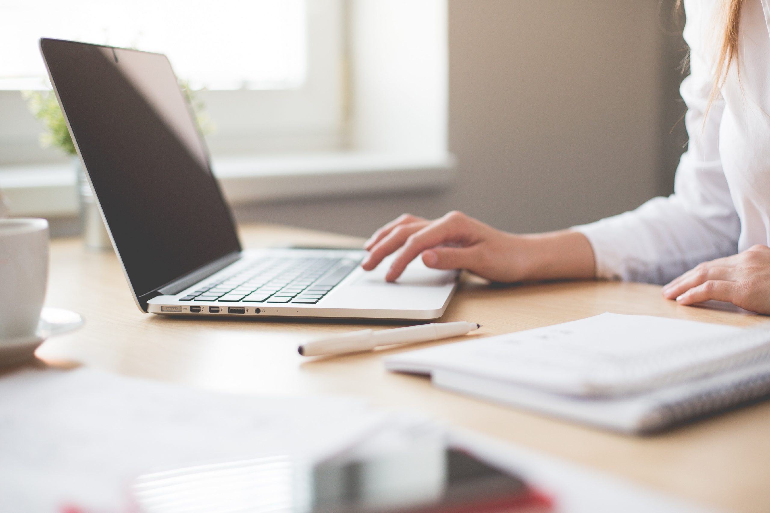 Image shows a person working on a laptop at a table.